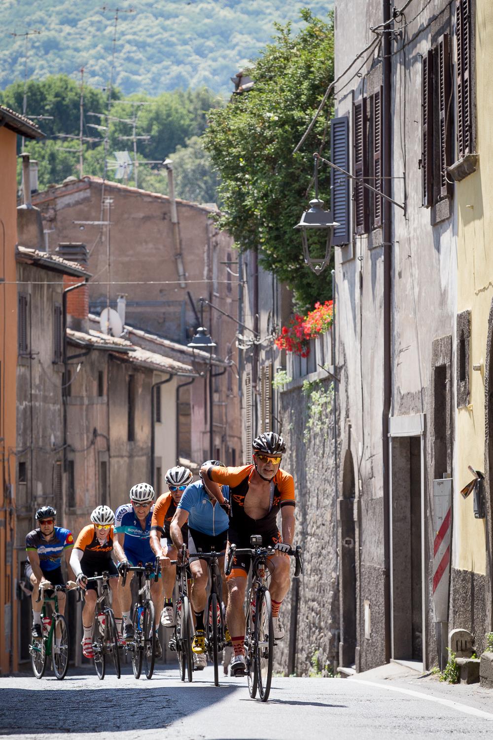 A group of cyclists riding through an Italian village
